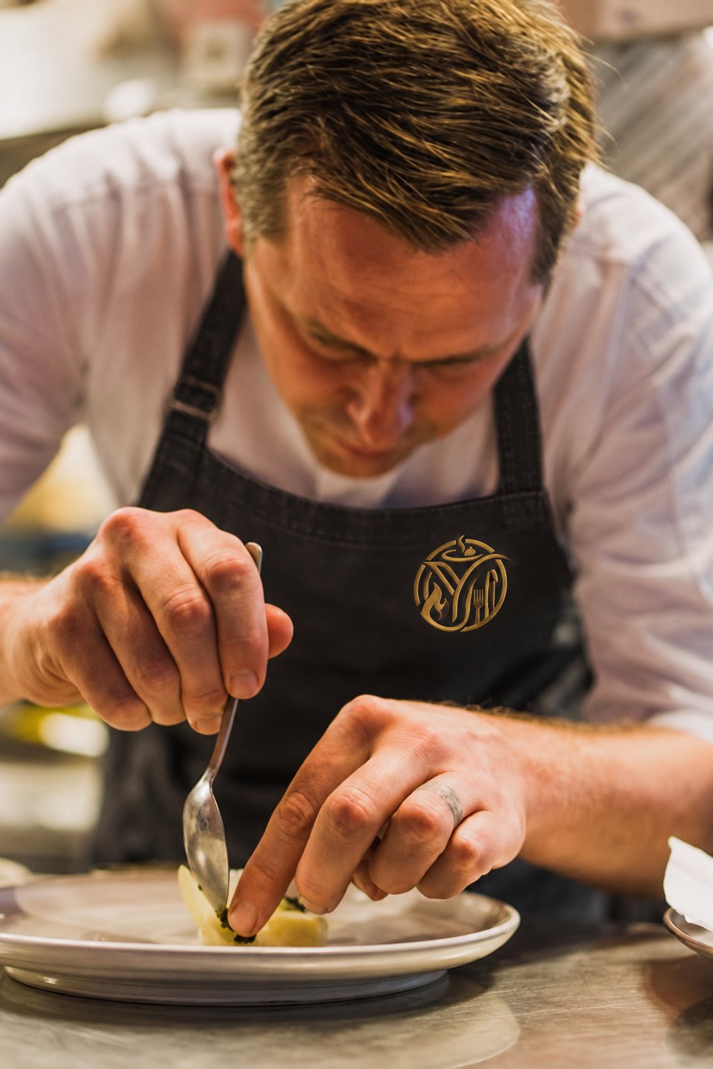 Chef Nic, wearing the Yunic apron, finishing a plate with careful precision